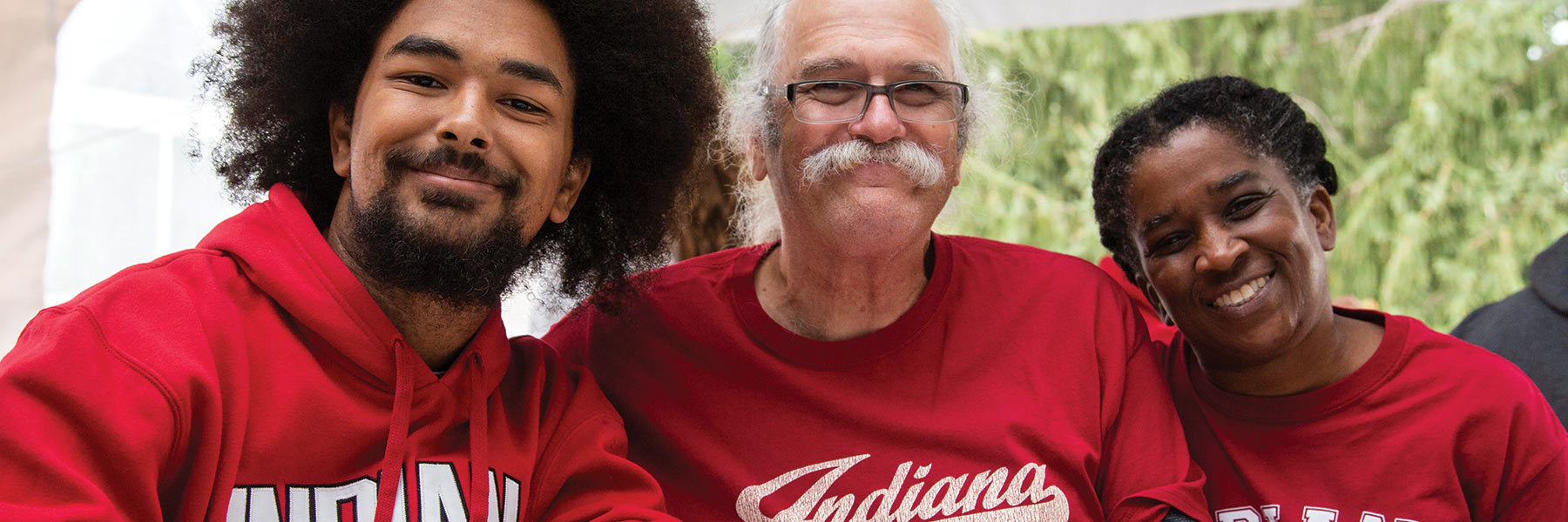 a mother and father smiling with their son. All three are wearing Indiana University shirts